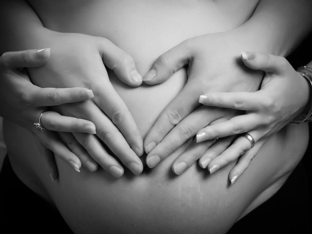 gravidfotografering med blivande mammas och pappas händer  runt magen